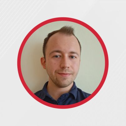 Mężczyzna w granatowej koszuli uśmiecha się w okrągłej ramce na jasnym tle.