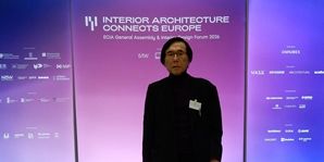 Mężczyzna stoi przed kolorowym tłem z napisem "Interior Architecture Connects Europe" na forum 2019.