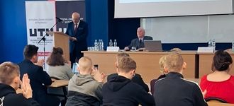 Podczas konferencji w Płońsku, prelegent wygłasza przemówienie do słuchaczy siedzących w sali.