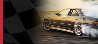Samochód wyścigowy driftuje na torze, w tle widać flagę szachową, symbolizującą motorsport.