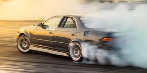 Samochód driftingowy kreuje chmurę dymu na torze wyścigowym w dynamicznej akcji motorsportu.