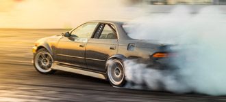 Samochód driftingowy kreuje chmurę dymu na torze wyścigowym w dynamicznej akcji motorsportu.