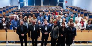 Uczestnicy konferencji oświatowej w UTH stoją razem w sali wykładowej, uśmiechając się do zdjęcia.