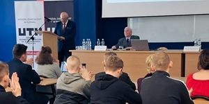 Podczas konferencji w Płońsku, prelegent wygłasza przemówienie do słuchaczy siedzących w sali.